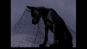 A huge dog statue towers above a man. 